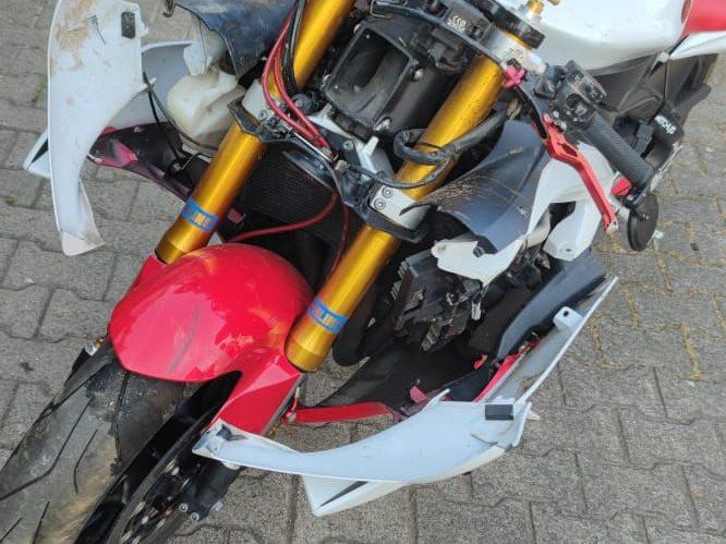 Front eines gestürzten Sportmotorrads mit gebrochener Verkleidung und freiliegender Gabel