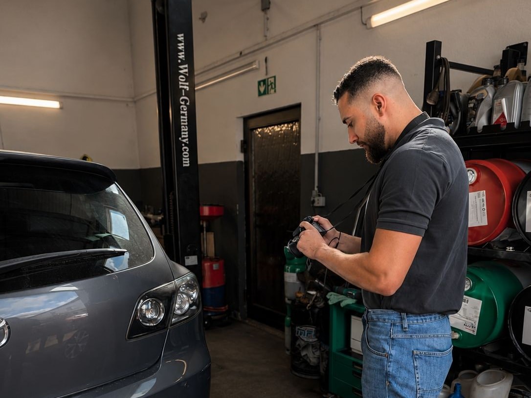 Josha Schumacher fotografiert in der Werkstatt den Schaden an einem Fahrzeugheck